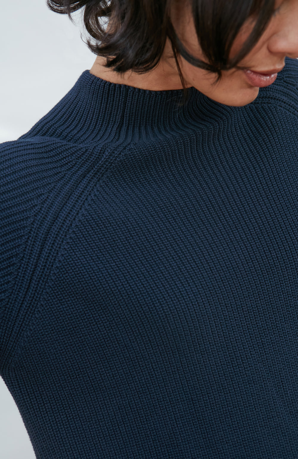 Woman wearing a dark navy ribbed knit mock-neck sweater by Paul James Knitwear