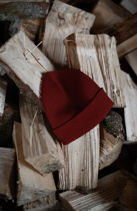 red merino wool womens beanie on logs by paul james knitwear