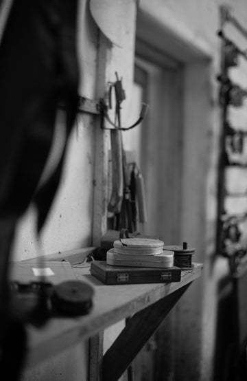 Black and white photograph of a workshop with tools and equipment on a table.