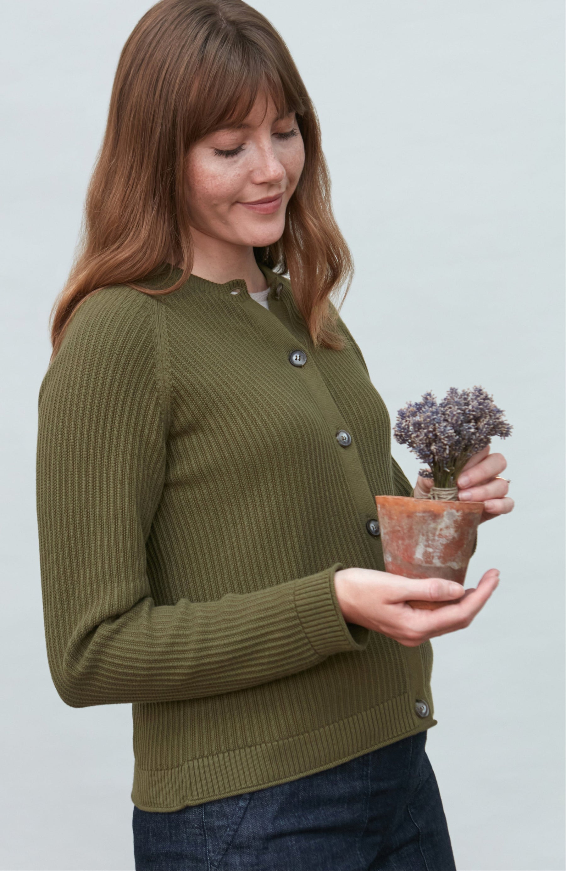 Woman wearing a green knitted cardigan sweater by paul james knitwear