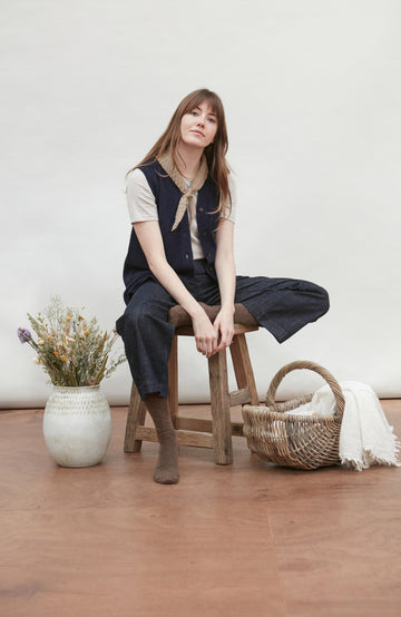 Woman wearing a navy wool vest and with a beige bow