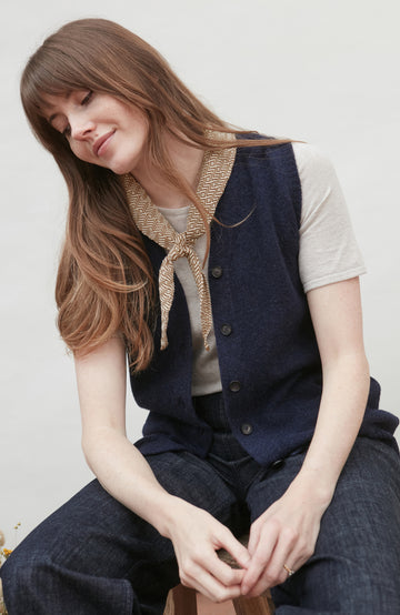 Woman wearing a navy wool vest and with a beige bow