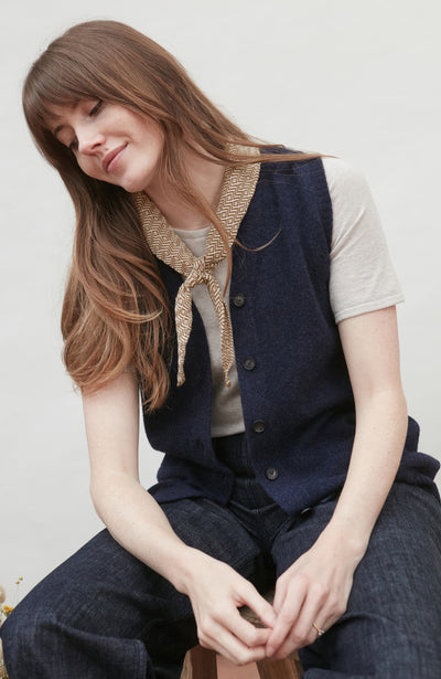 Woman wearing a navy wool vest and with a beige bow