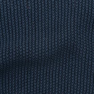 Woman wearing a blue knitted neck tie and scarf against a plain background by Paul James