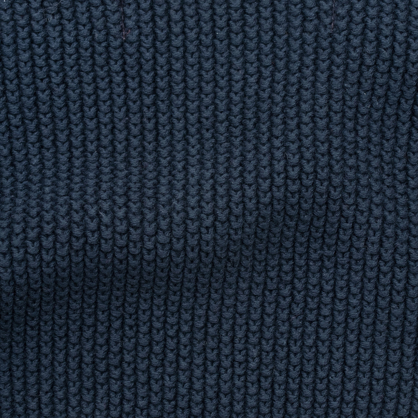 Woman wearing a blue knitted neck tie and scarf against a plain background