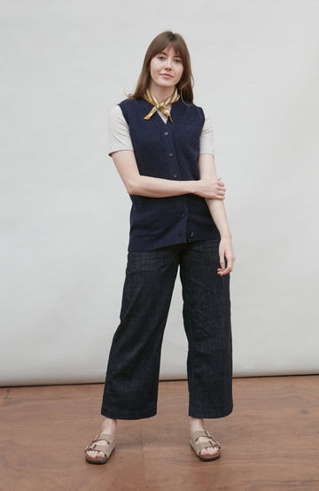 Woman wearing a stripe bandada navy wool sleeveless top and dark pants against a plain background by Paul James
