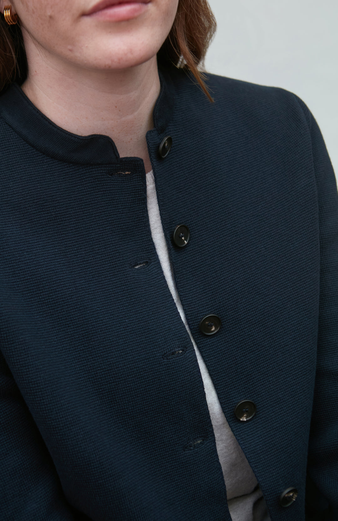 Close-up of a person wearing a dark blue textured nehru jacket with buttons.