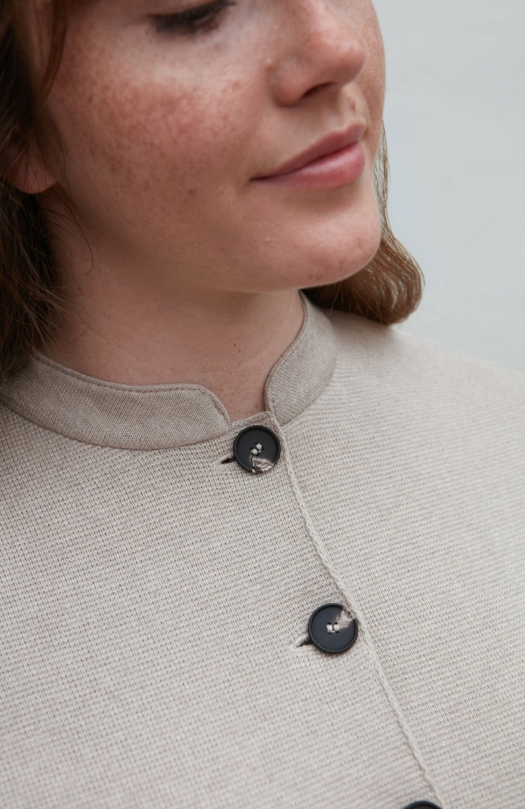 Close-up of a woman wearing a light-colored nehru jacket with black buttons.
