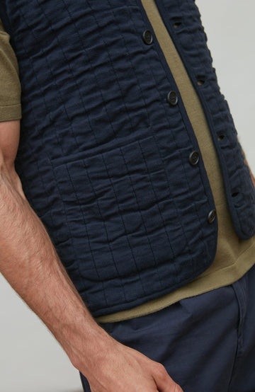 Navy quilted vest with button details on a neutral background