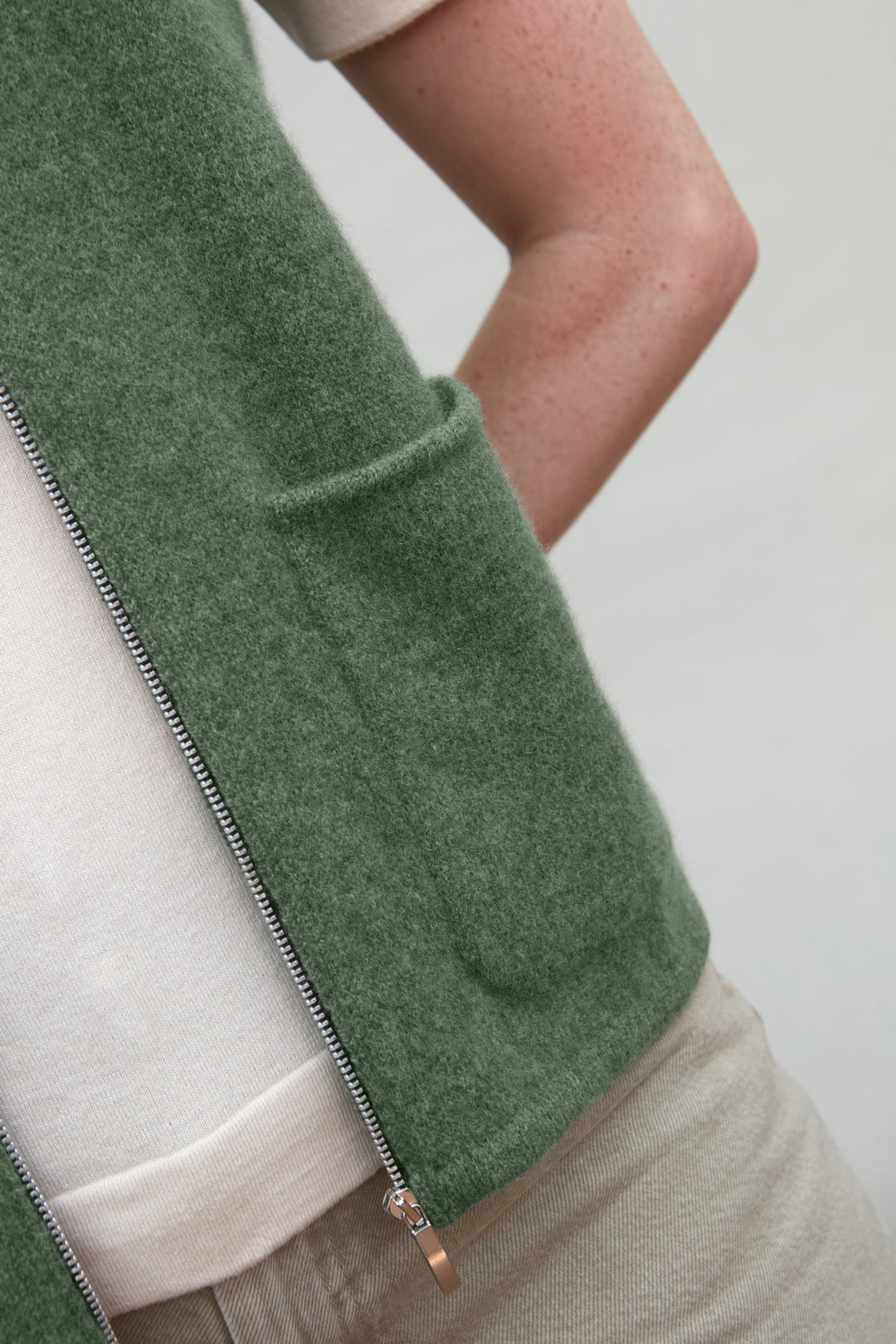 Green wool gilet by paul james with a zipper on a neutral background