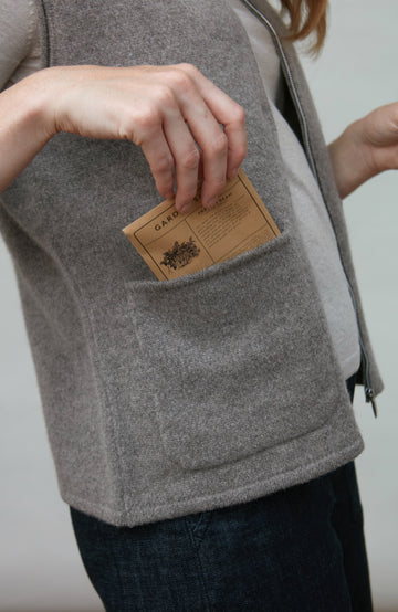 Person wearing a gray wool gilet by paul james with a patch on a plain background