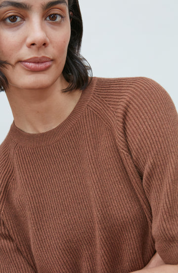 A womens rust ribbed knit short-sleeve sweater with a crew neck by paul james knitwear, displayed flat against a light gray background.