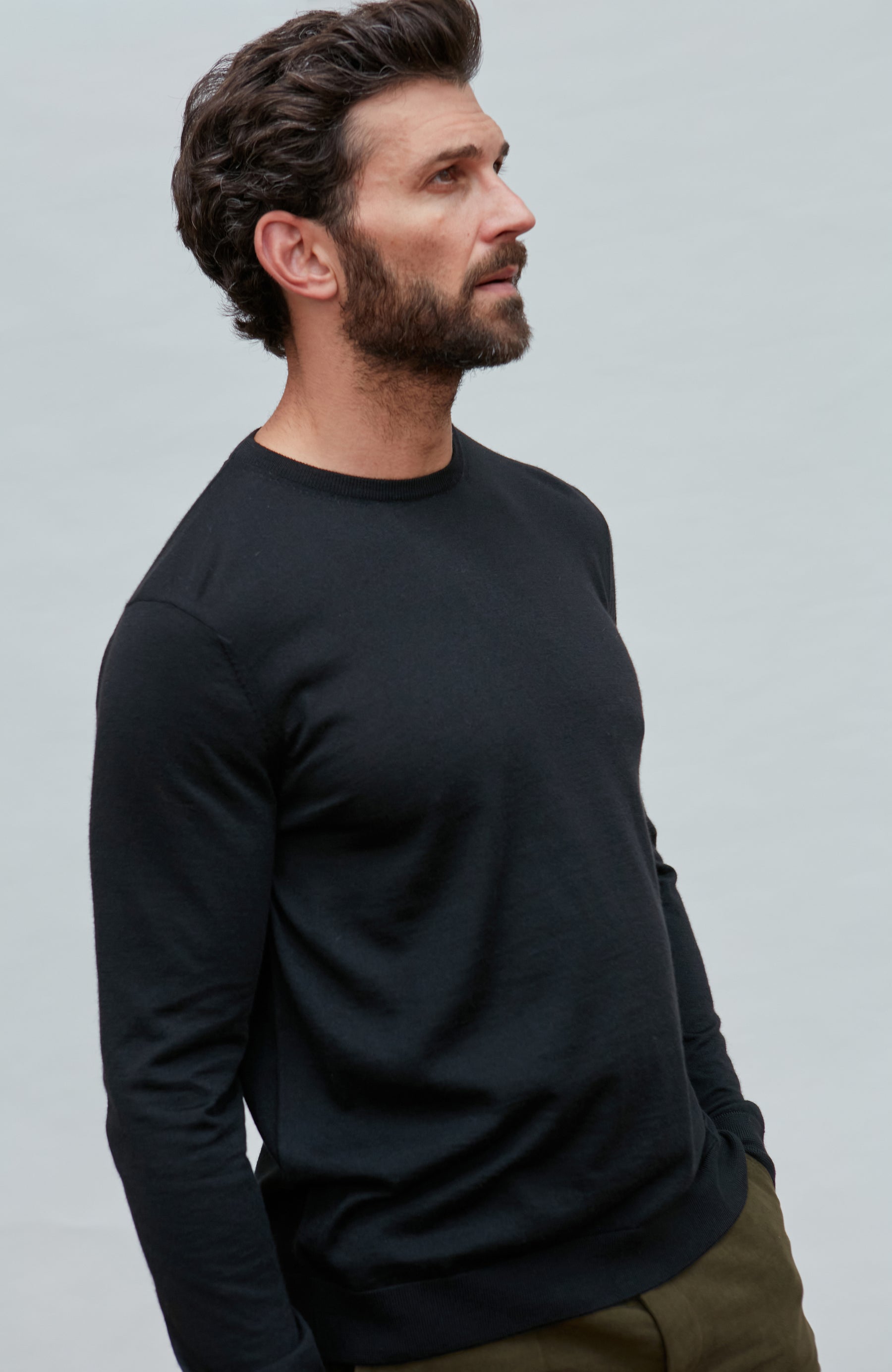 Man wearing a black merino silk long-sleeve shirt against a light gray background
