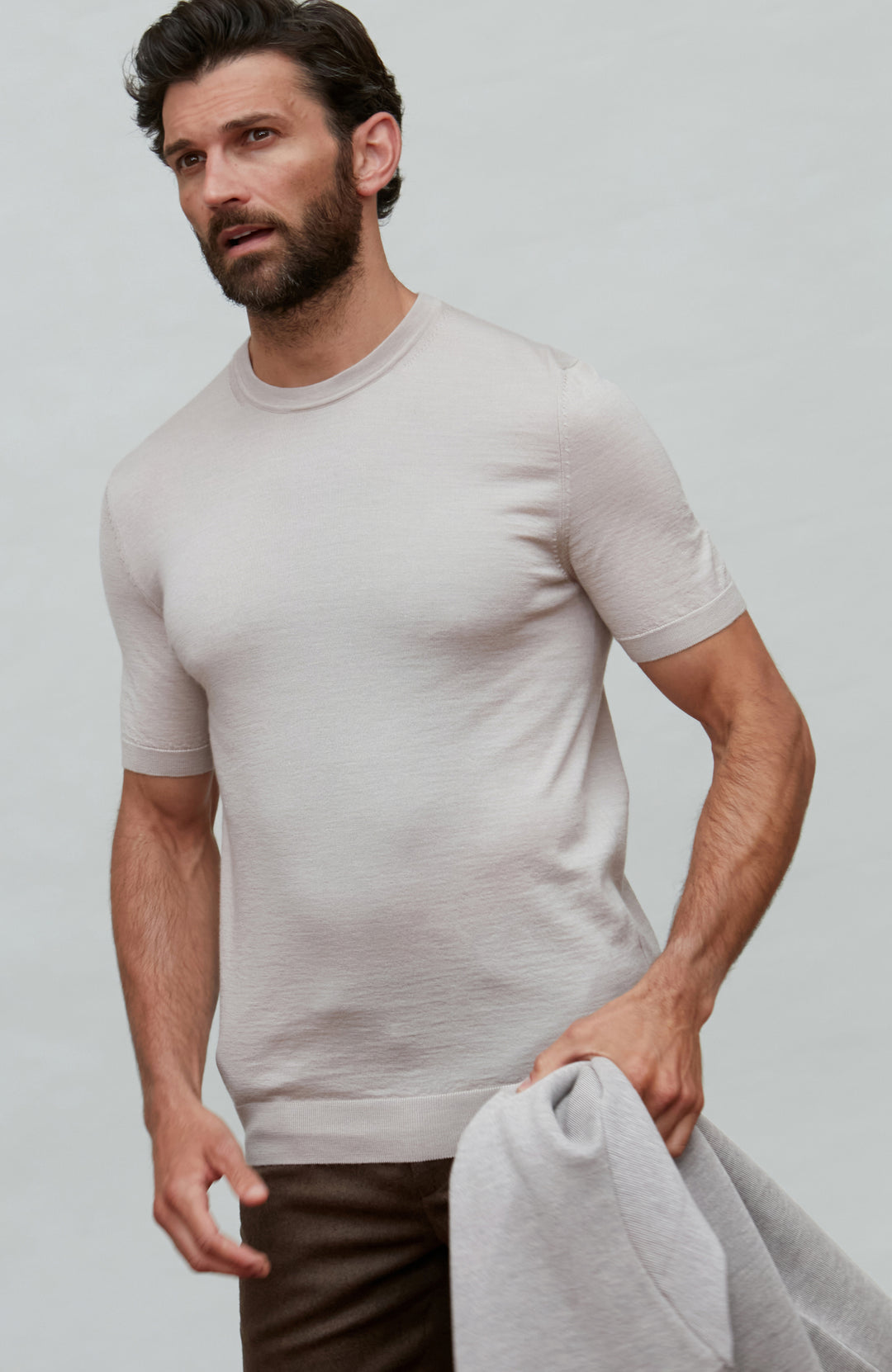 Man wearing a beige fine wool silk luxury t-shirt by Paul James against a plain background