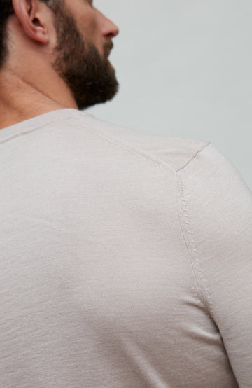 Close-up of a beige fine wool silk luxury t-shirt by Paul James worn by a person with a neutral background