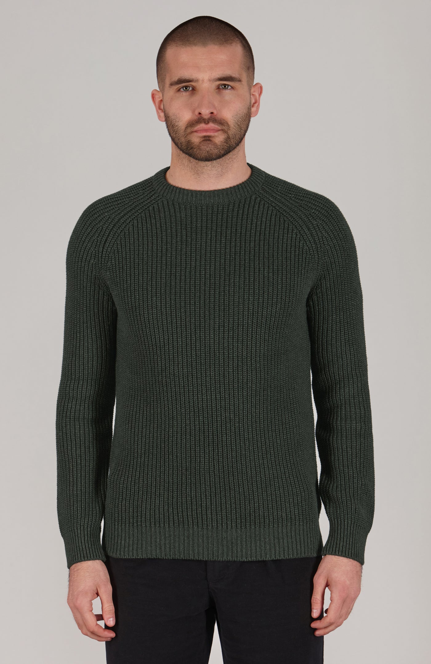 Man wearing a green ribbed sweater against a plain background