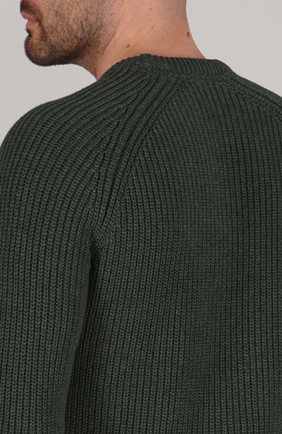 Green ribbed sweater worn by a person on a plain background