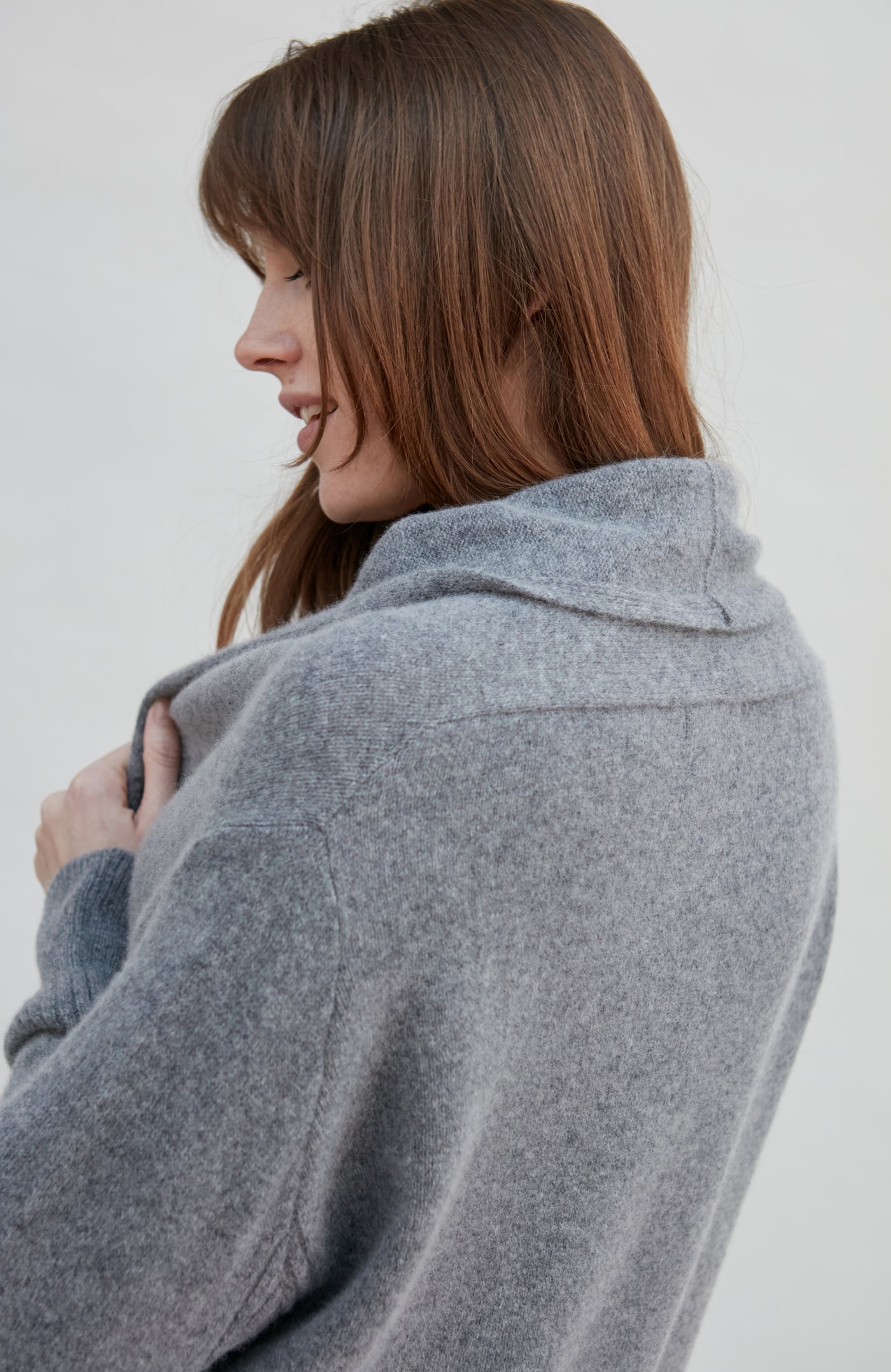 Woman wearing a gray wool cardigan against a white background