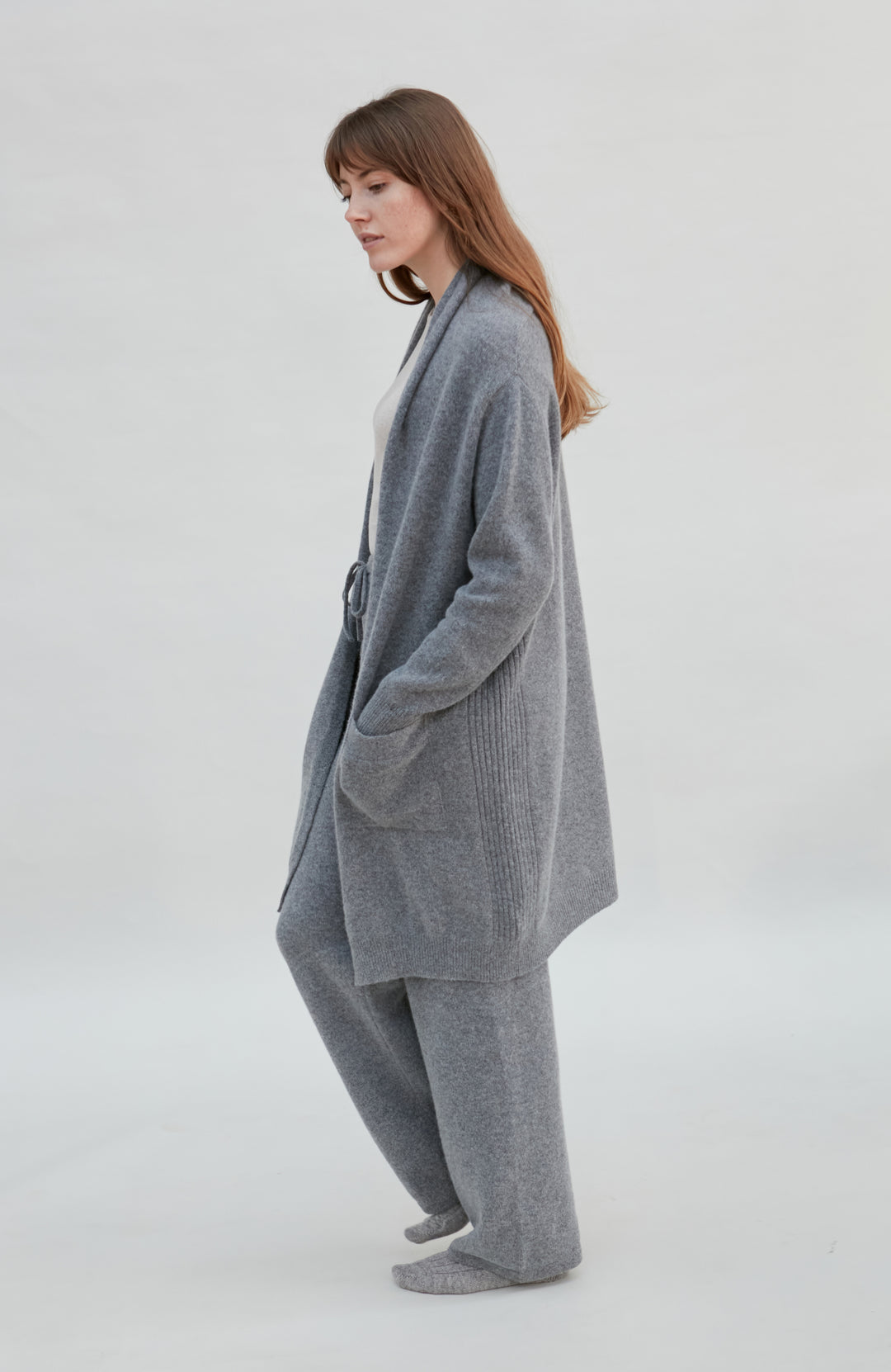 woman wearing a gray longline wool cardigan outfit on a white background by Paul James