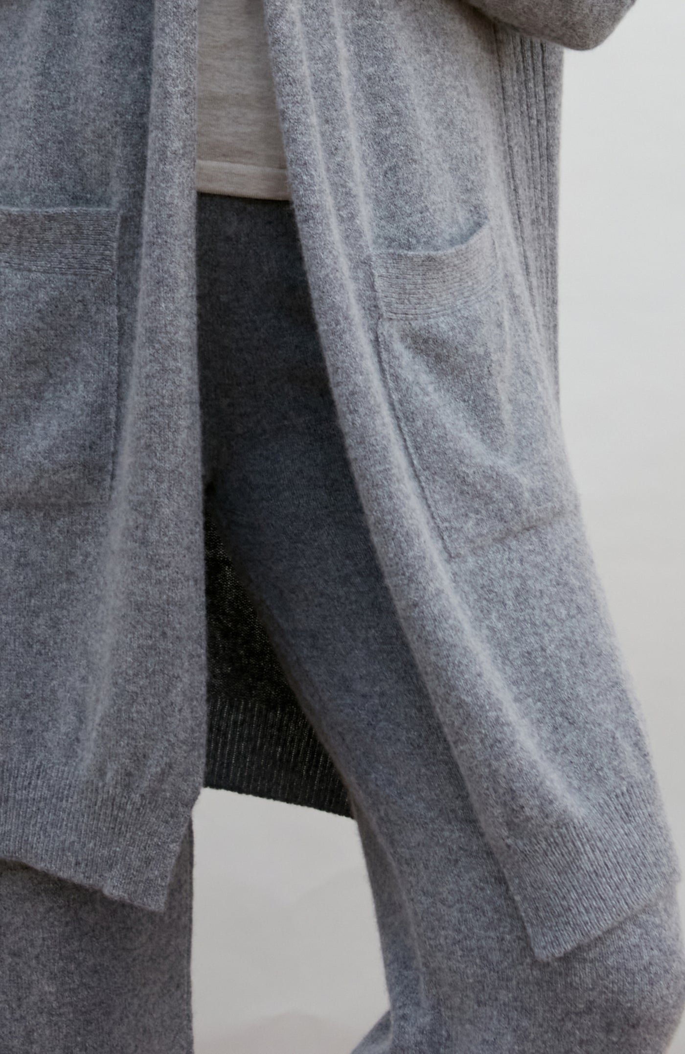 Gray cardigan worn by a person on a white background