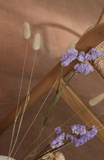 Purple flowers and dried grasses against a wooden background