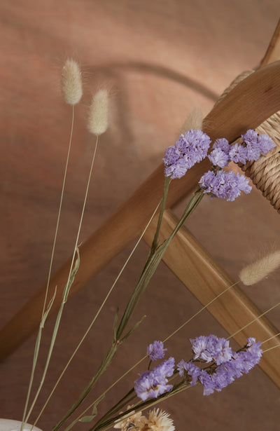 Purple flowers and dried grasses against a wooden background