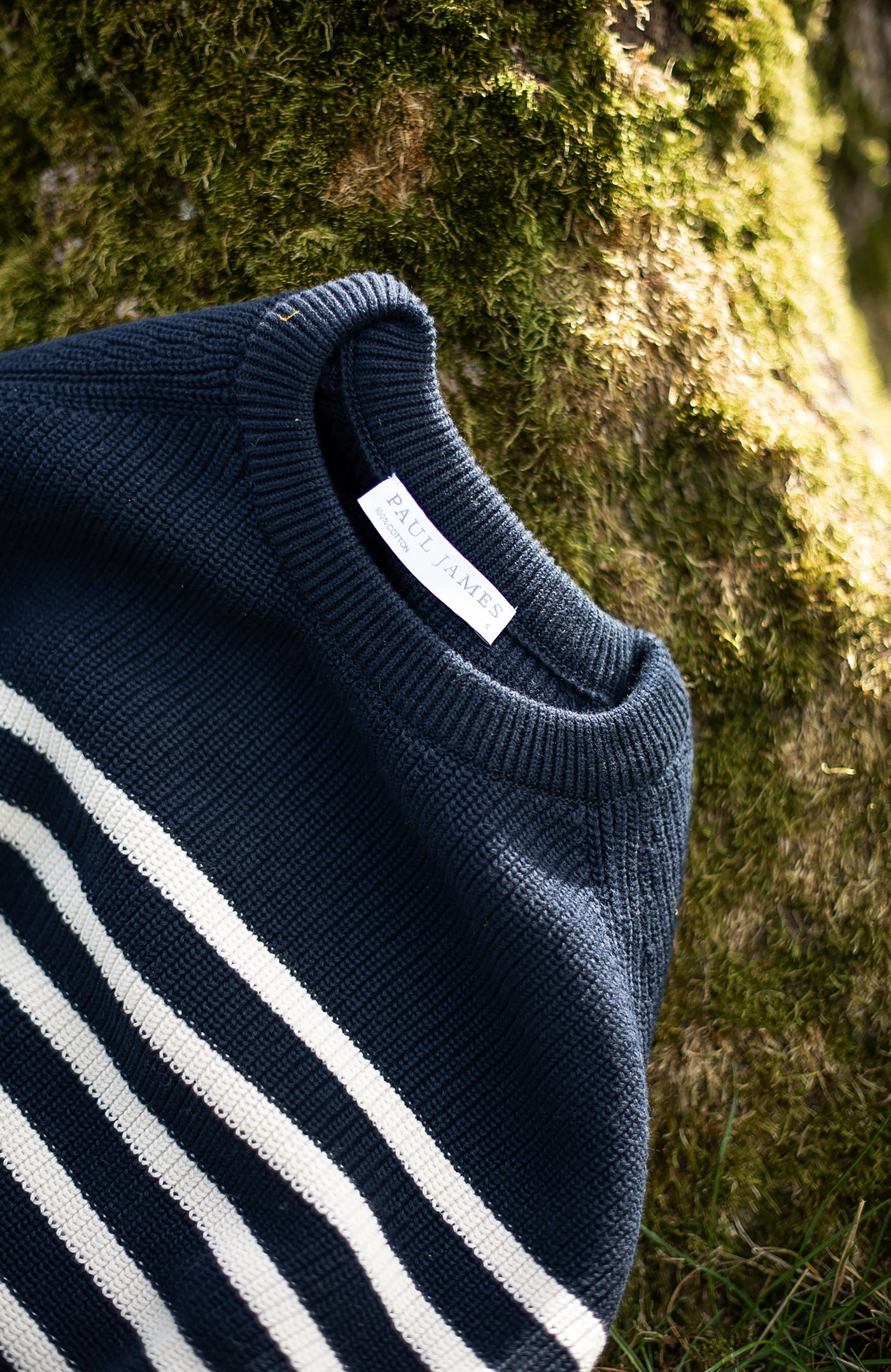 Navy blue sweater with white stripes against a natural background