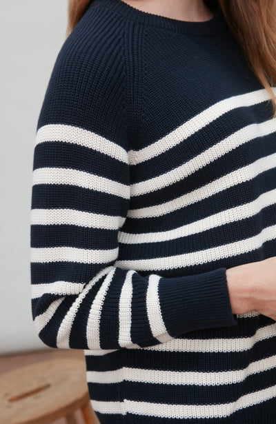 Navy and white striped cotton breton sweater worn by a person with a neutral background
