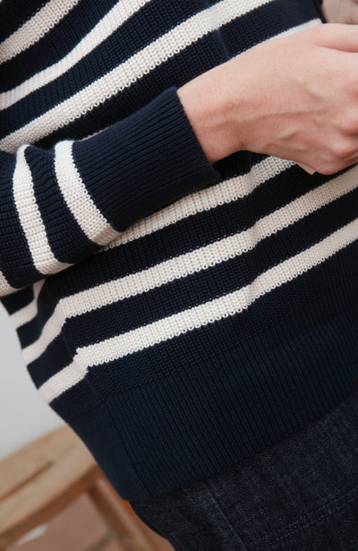 Close-up of a navy and white striped sweater with a blurred background