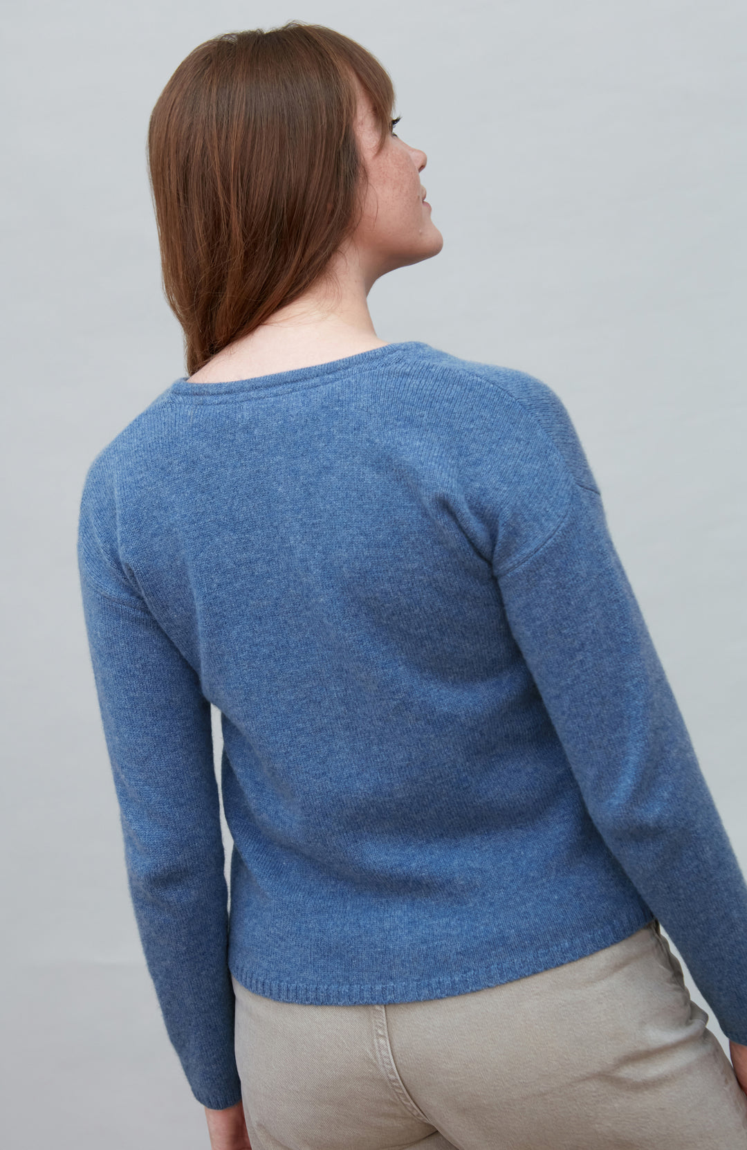 Woman wearing a blue wool sweater against a gray background by Paul James