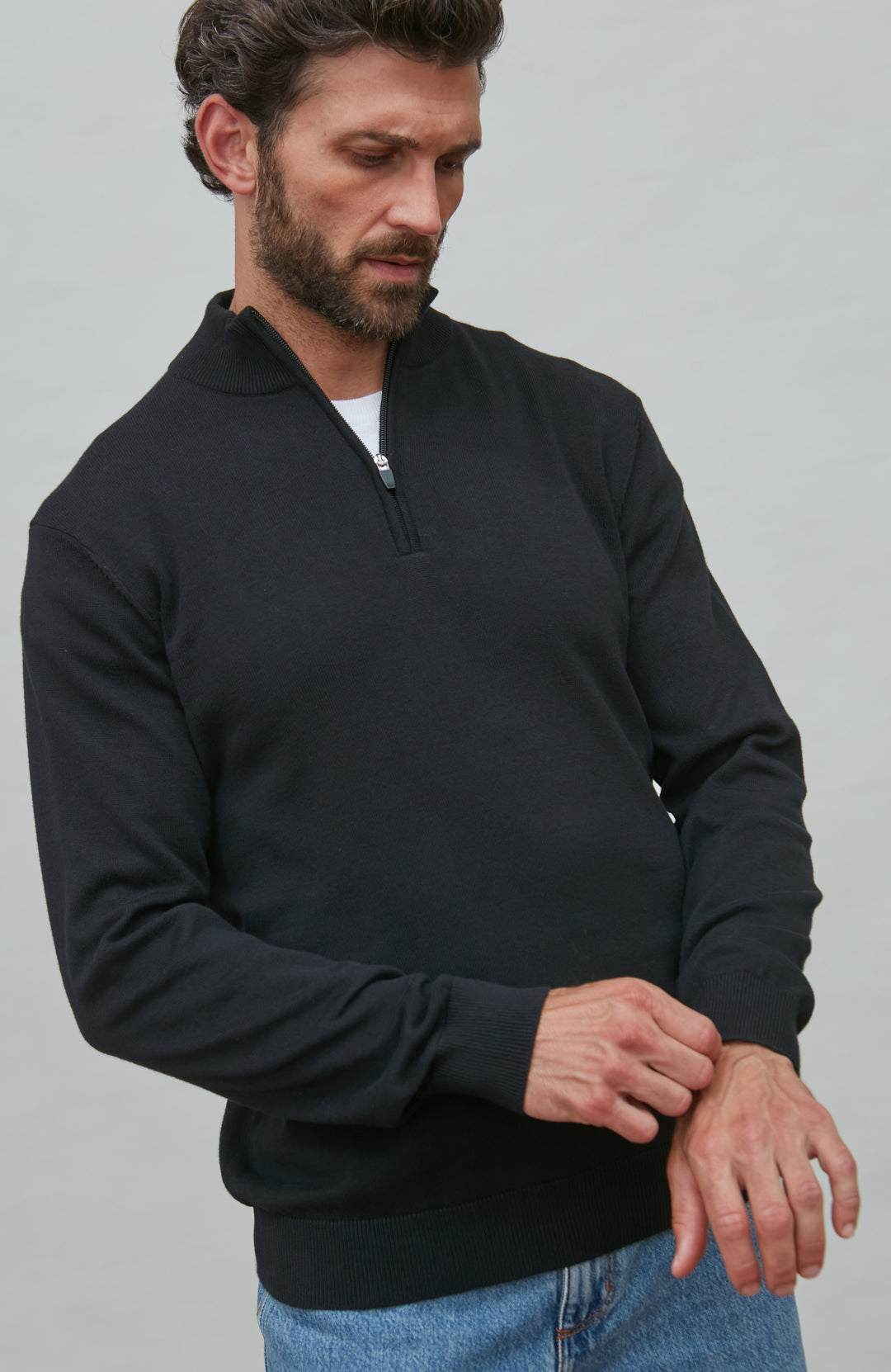 Man wearing a black quarter-zip sweatshirt against a gray background By Paul James