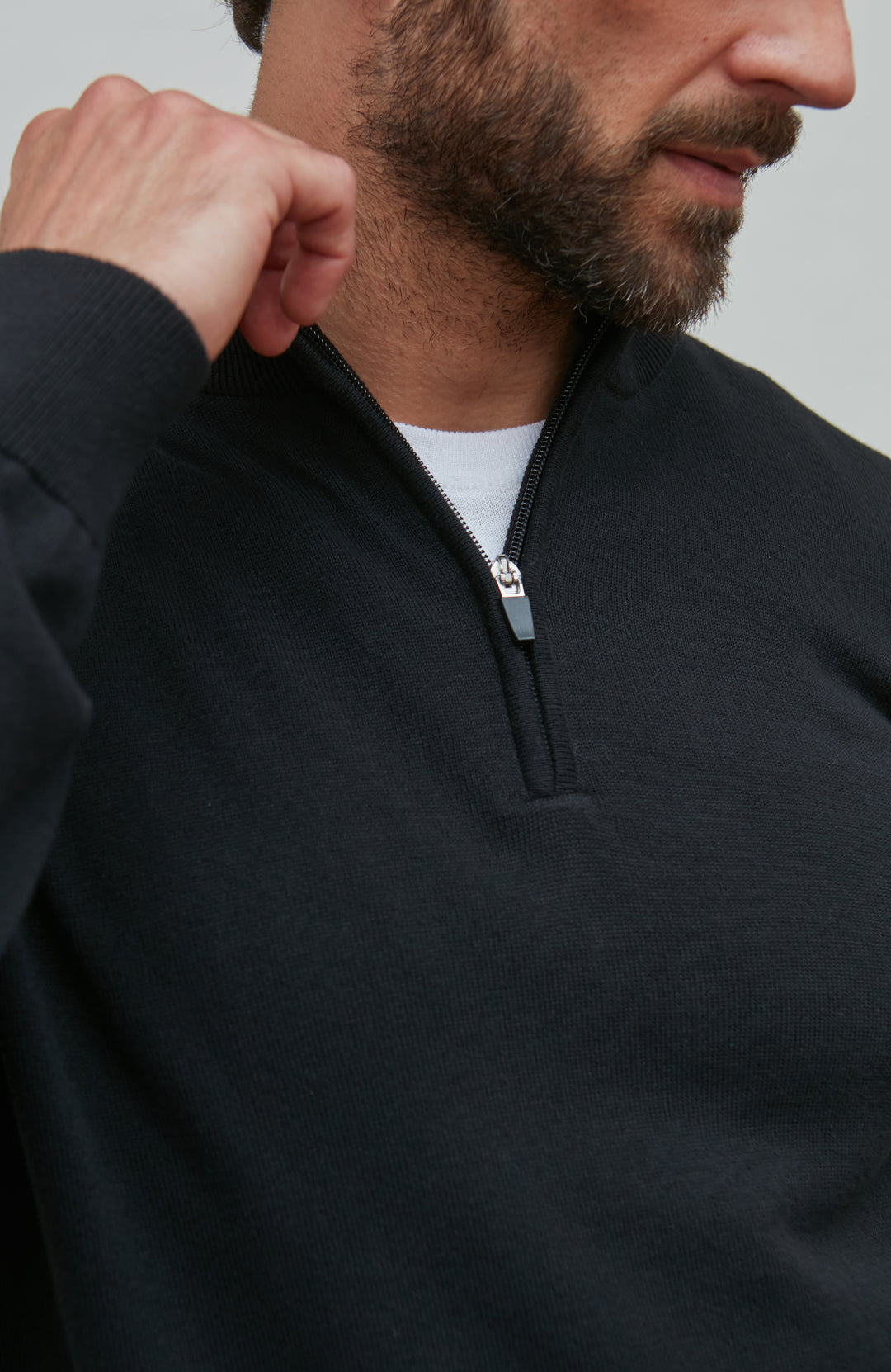 Man wearing a black quarter-zip sweatshirt with a plain background By Paul James