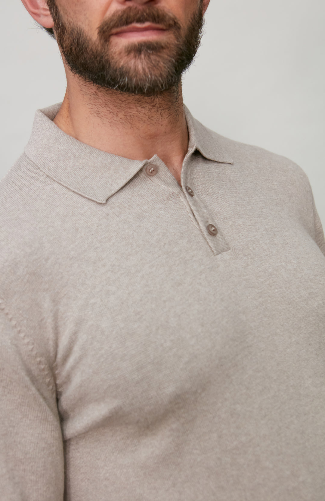 Man wearing a beige polo shirt against a plain background