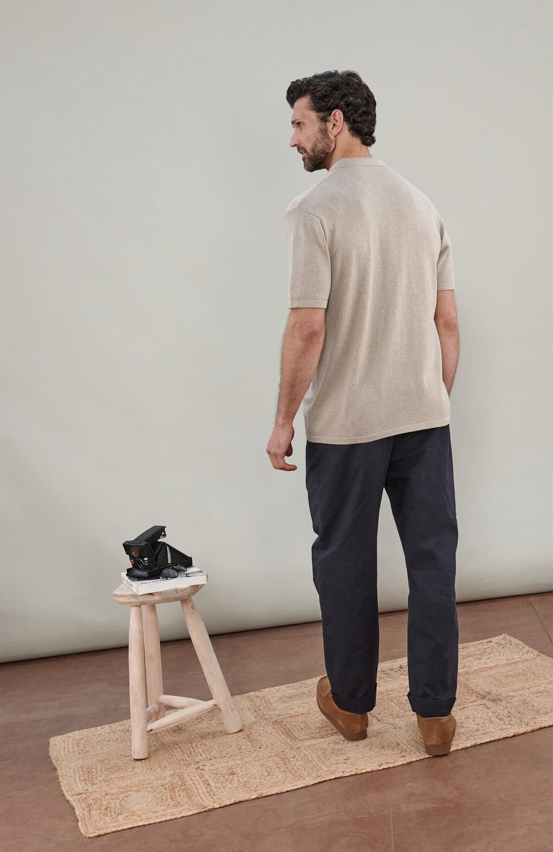 A man wearing a light beige short-sleeve cotton knit button-up shirt by paul james knitwear