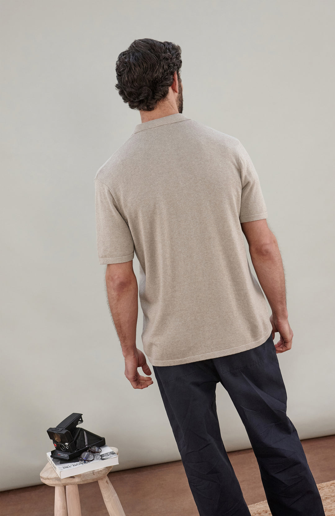 A man wearing a light beige short-sleeve cotton knit button-up shirt by paul james knitwear