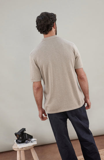 A man wearing a light beige short-sleeve cotton knit button-up shirt by paul james knitwear