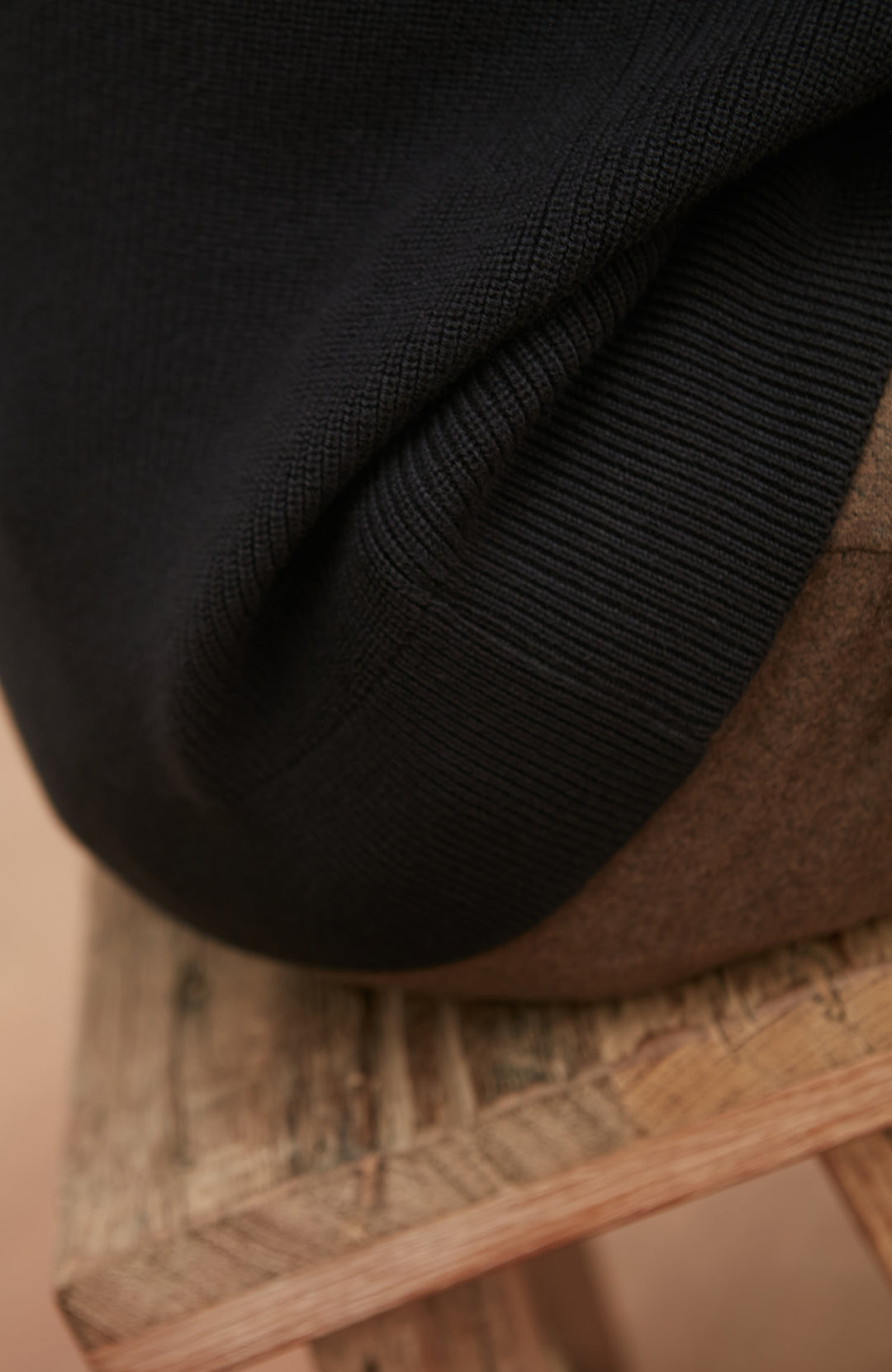 Close-up of a black rib jumper on a woven surface