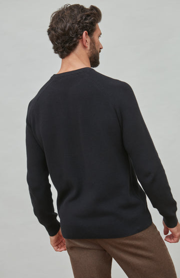 Man wearing a black fisherman sweater on a gray background
