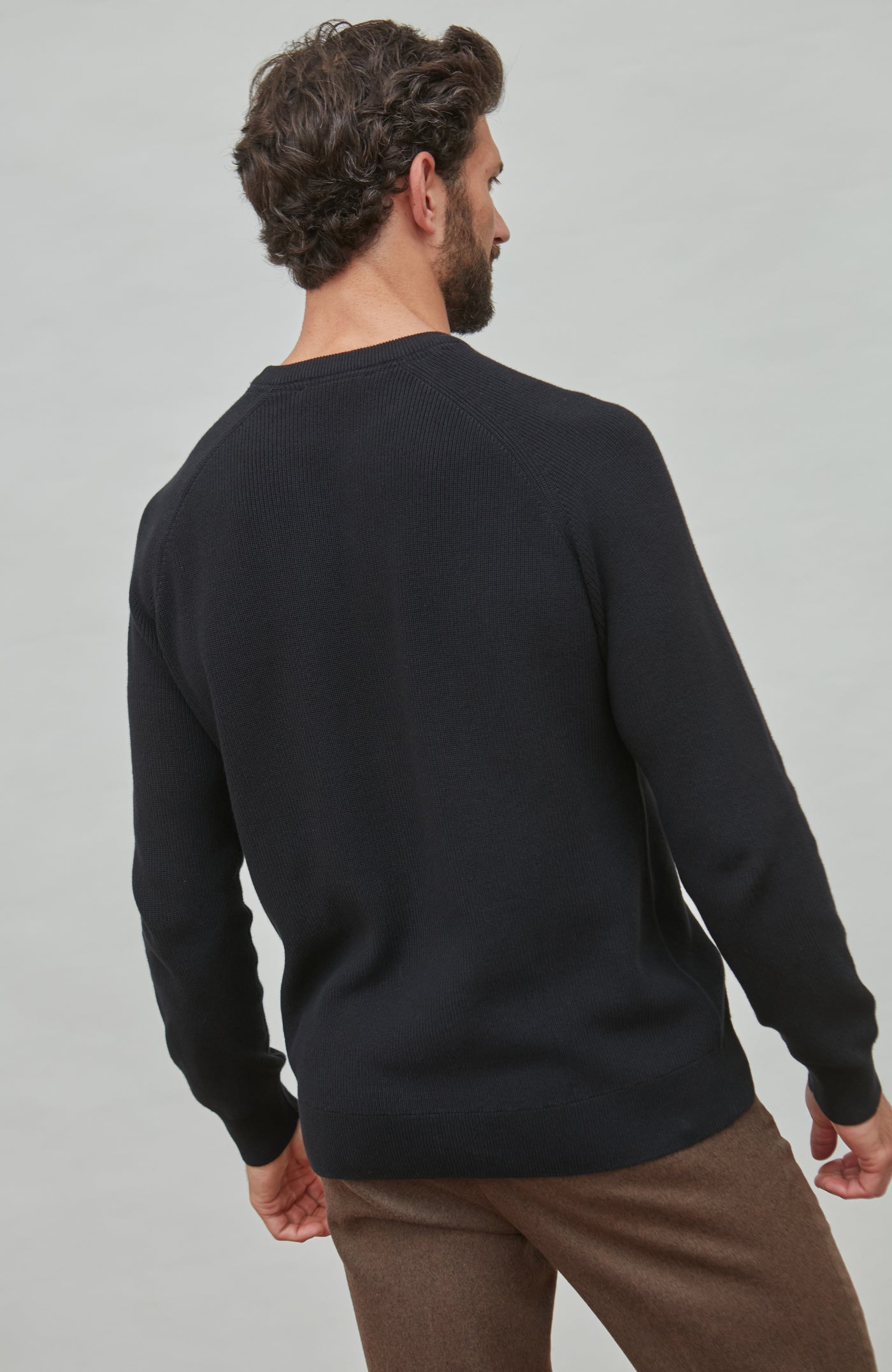 Man wearing a black fisherman sweater on a gray background