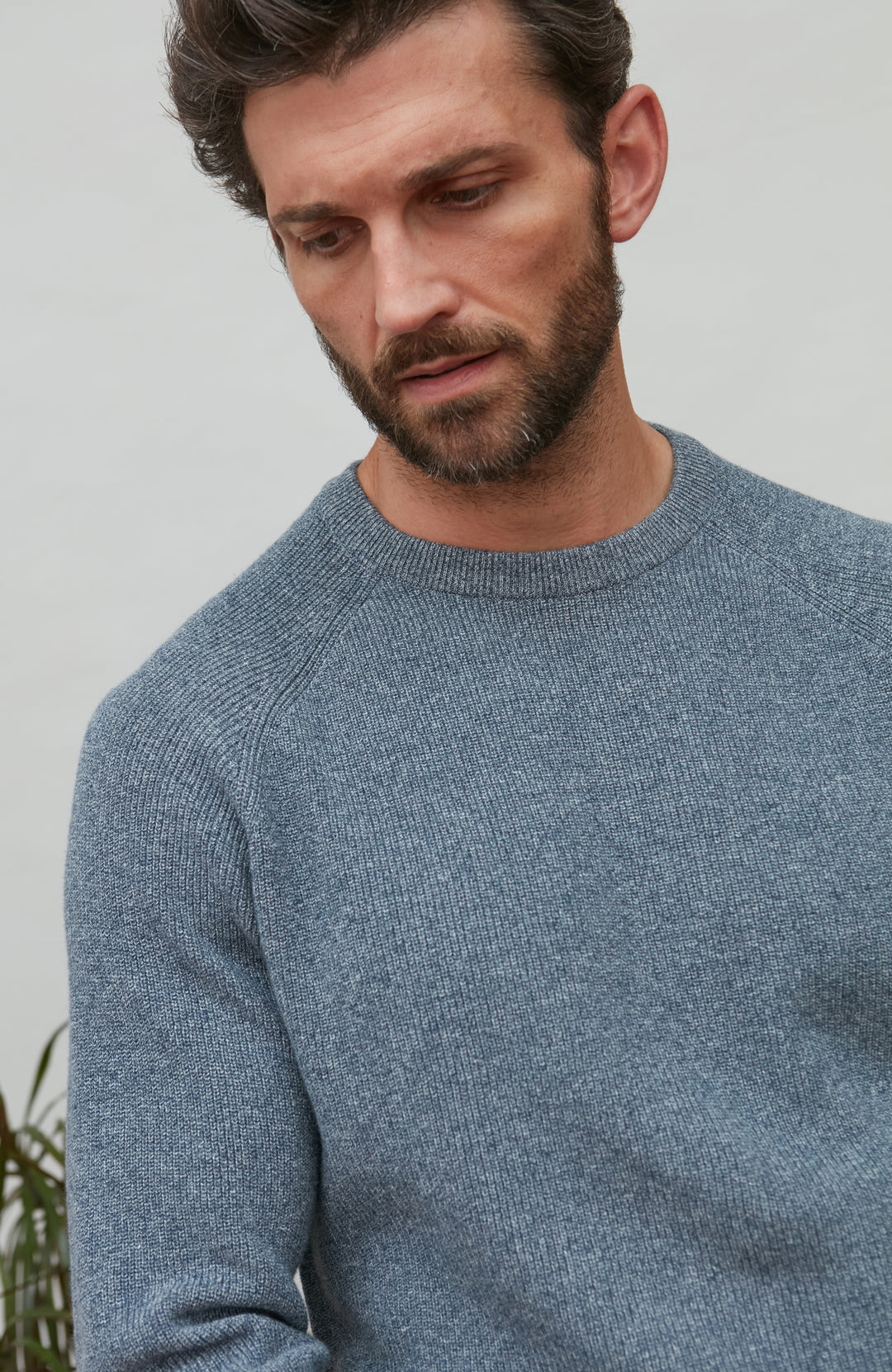 Man wearing a blue cotton rib sweater against a plain background