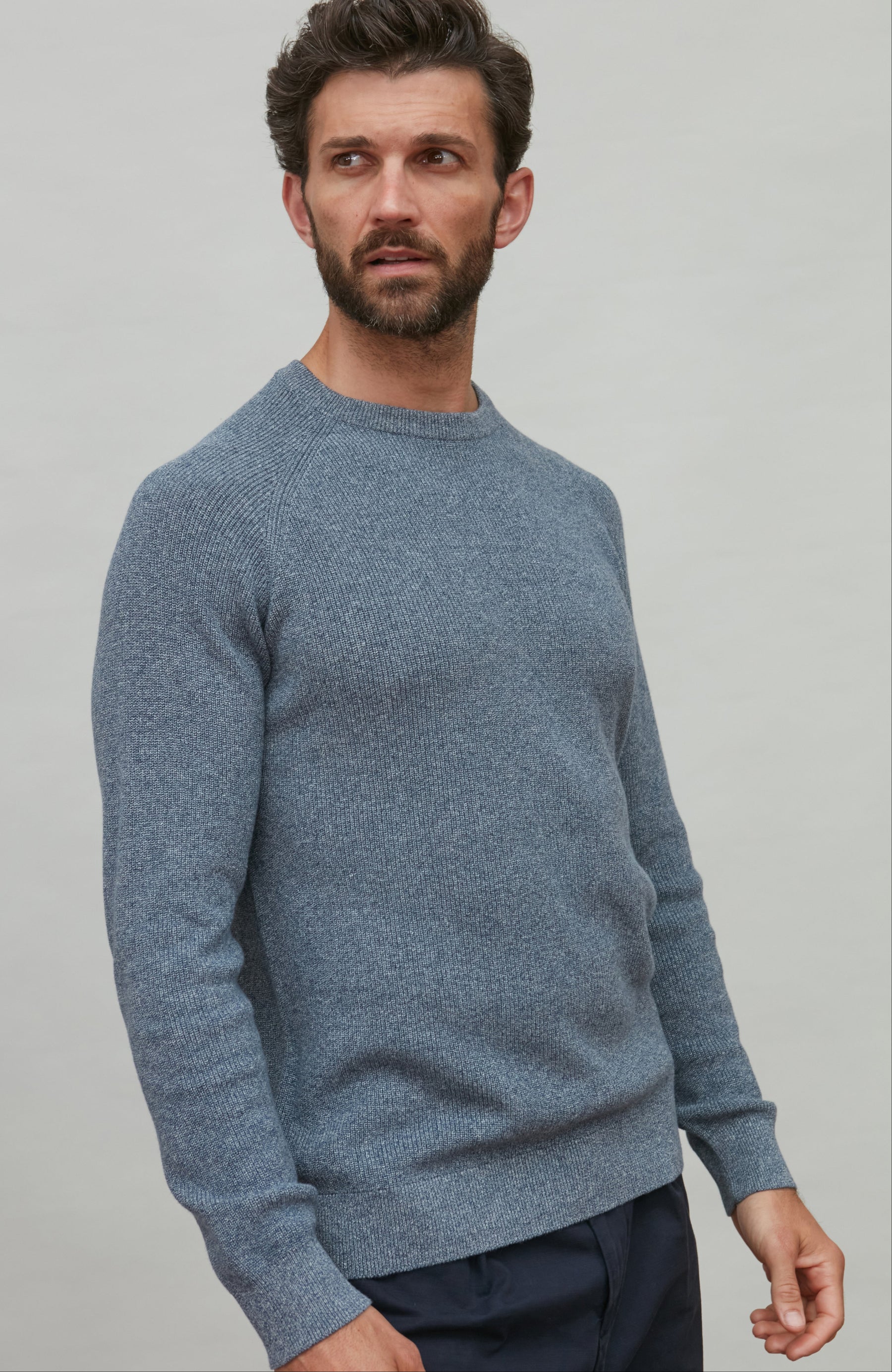 Man wearing a blue cotton rib sweater against a plain background
