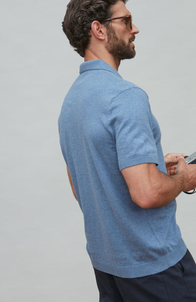 Man wearing a blue polo shirt against a gray background