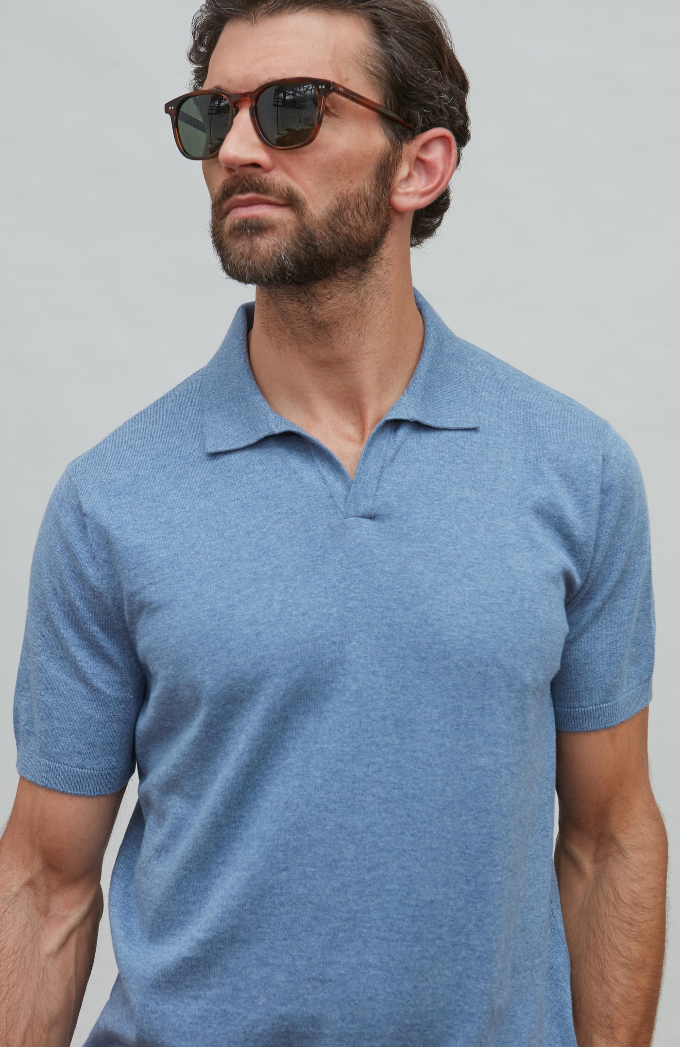 Man wearing a blue polo shirt against a gray background