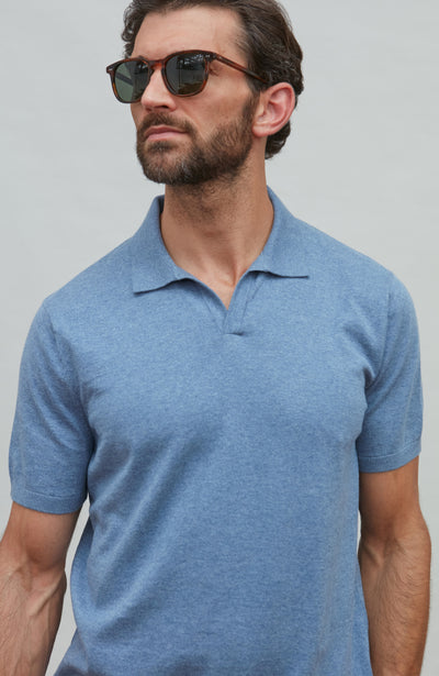 Man wearing a blue polo shirt against a gray background