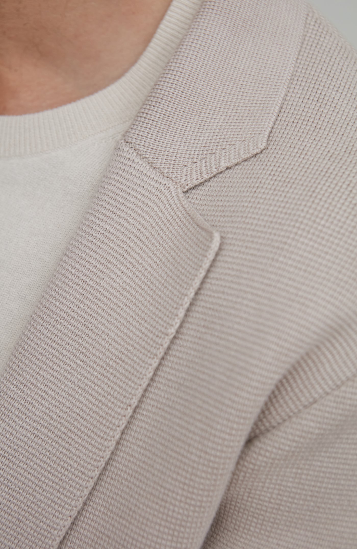 Close-up of a textured beige cardigan and sweater