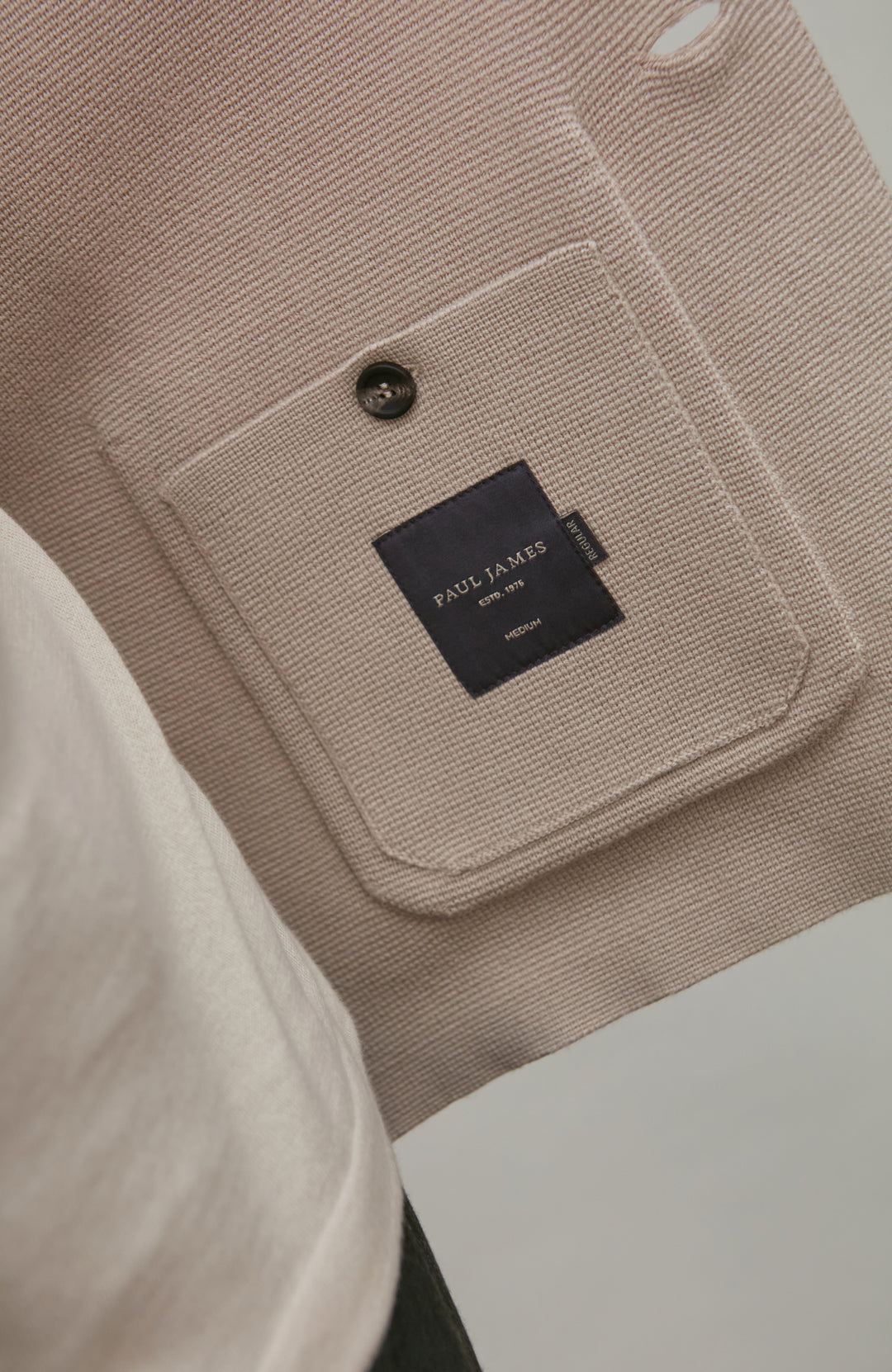 Close-up of a beige fabric pocket with a black label on a white background