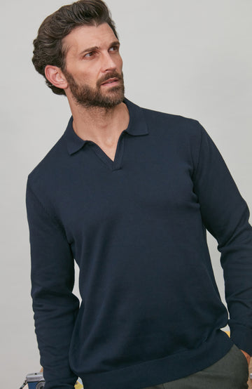 Man wearing a navy long-sleeve cotton polo shirt against a gray background