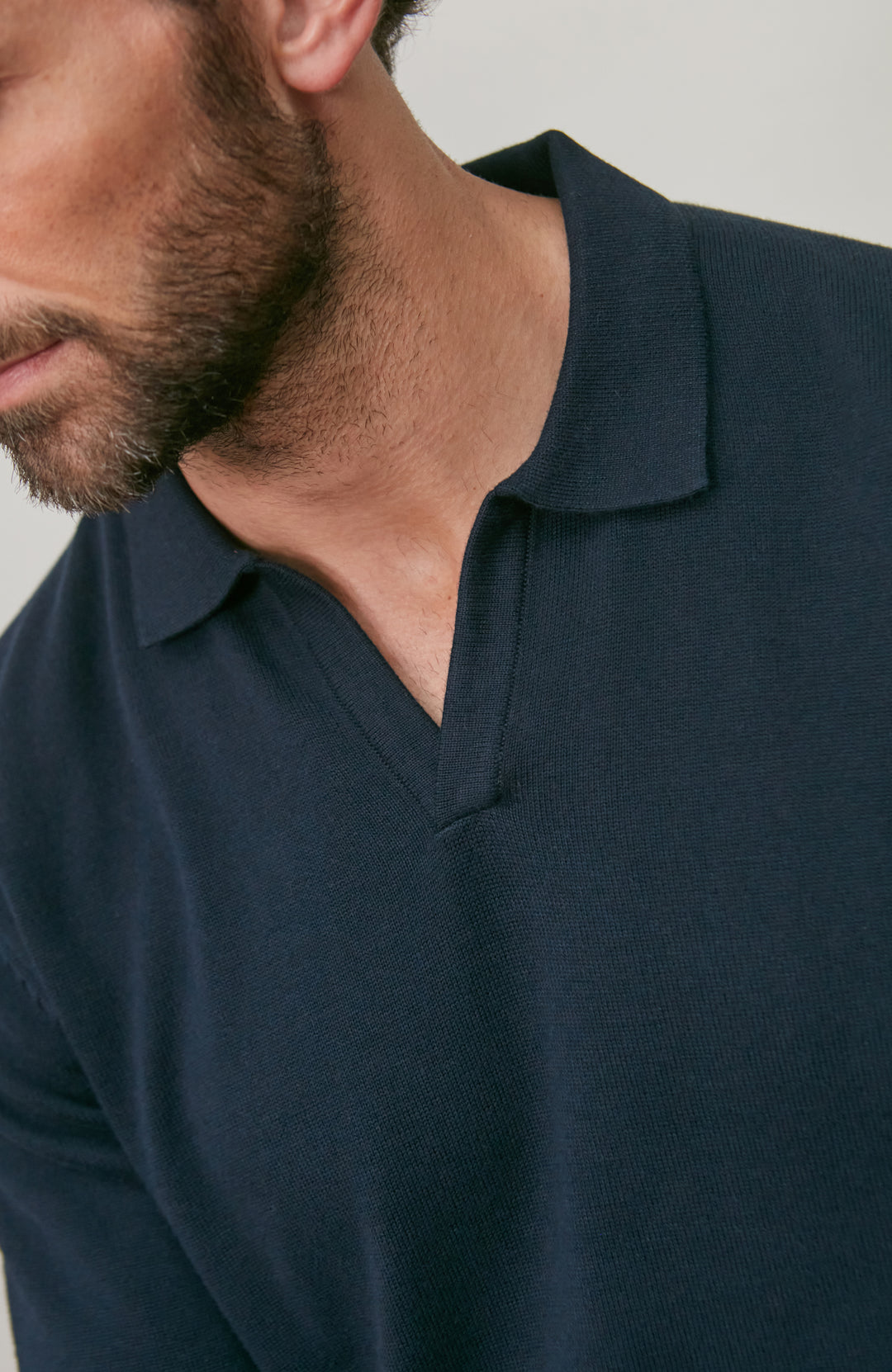 Man wearing a navy blue polo cotton polo shirt against a neutral background