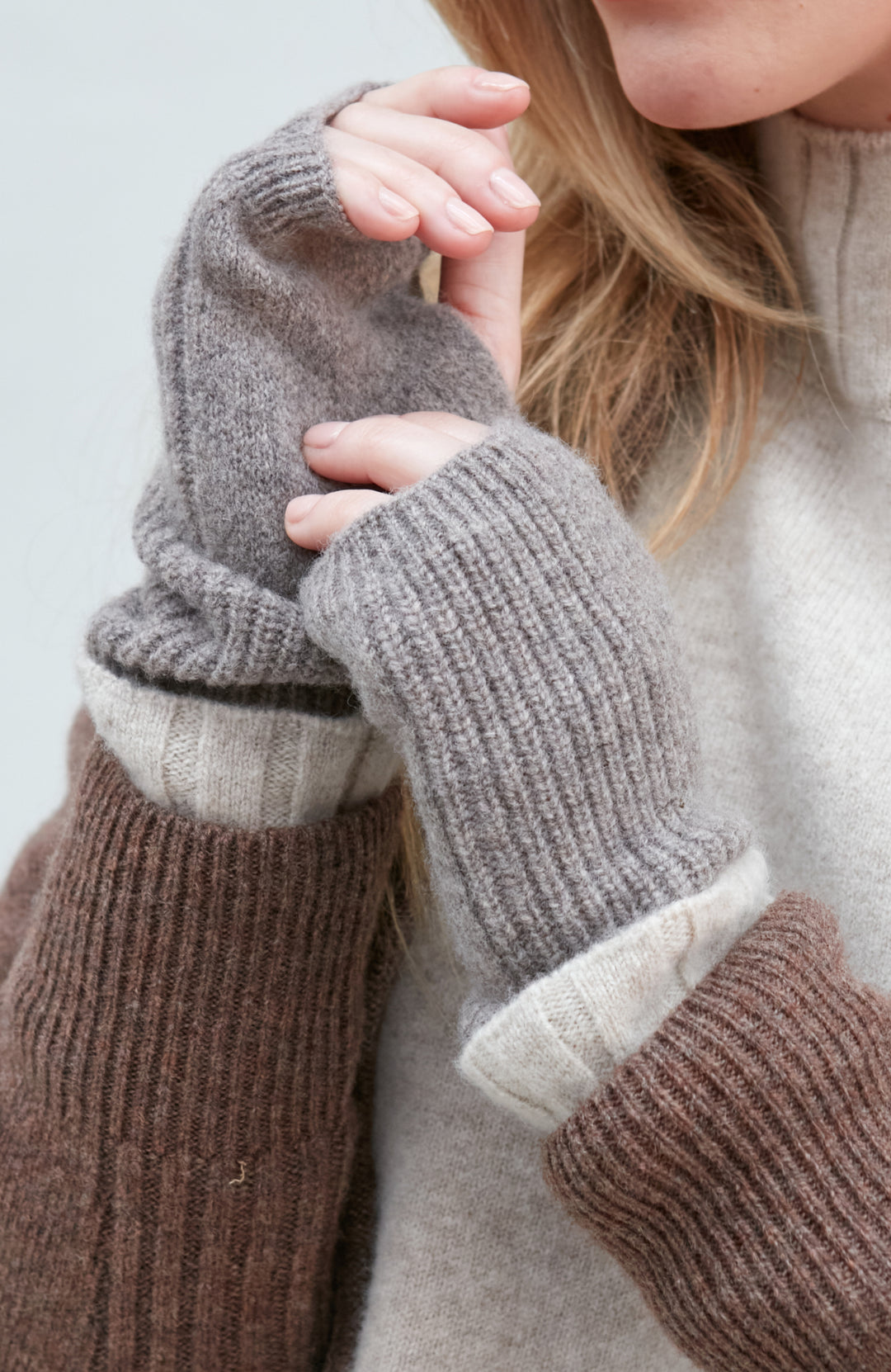 Close-up of a person wearing brown and gray wool knit mittens by Paul James