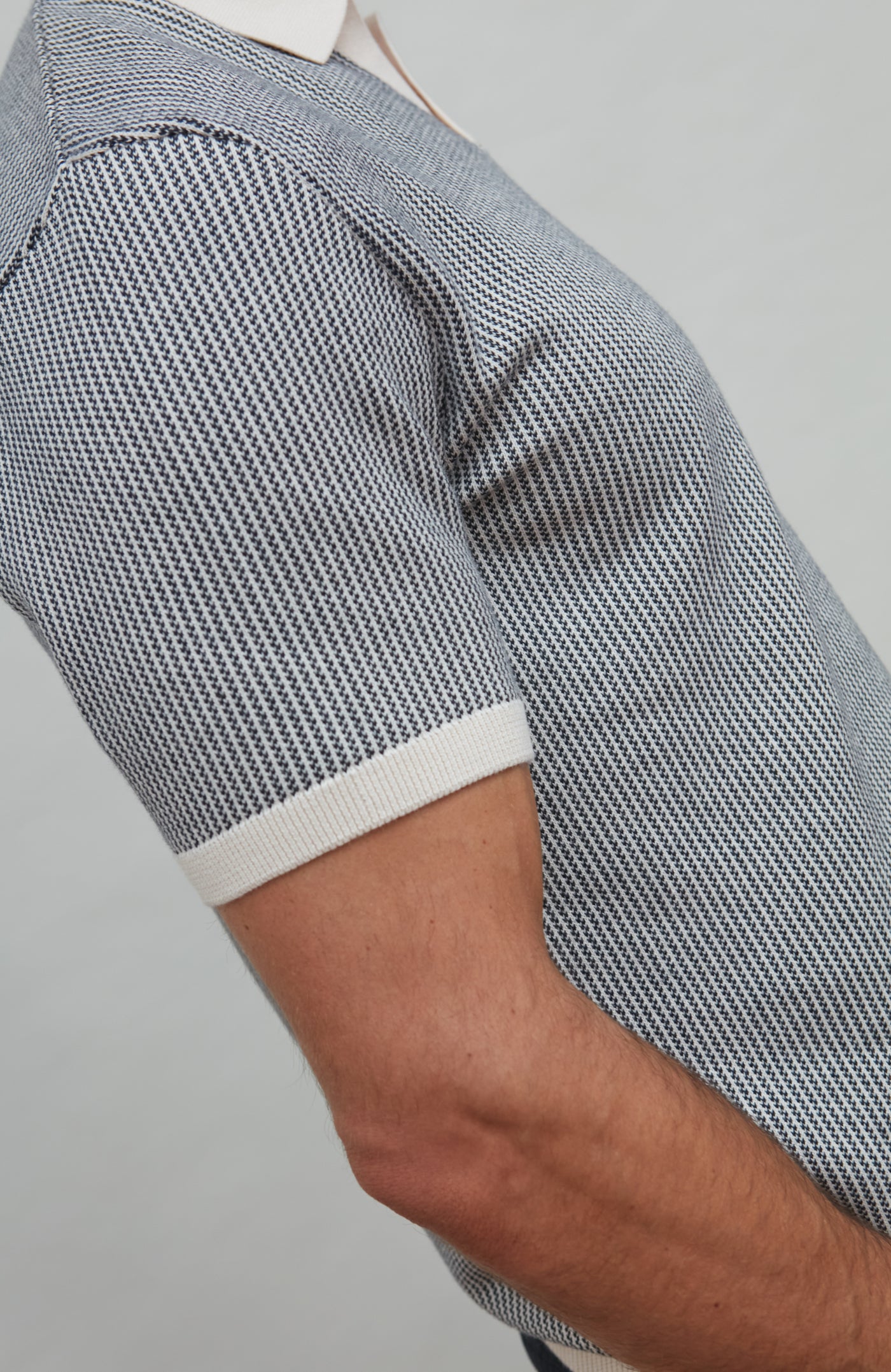 Close-up of a person wearing a patterned shirt with white trim on a gray background